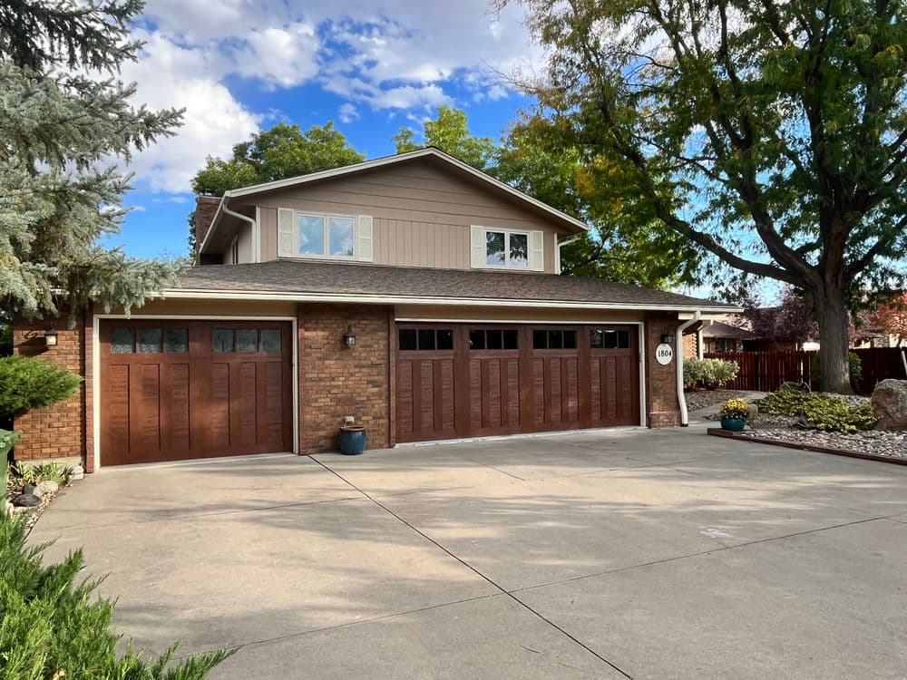 Two-story suburban home with brown wooden garage doors and landscaped front yard.