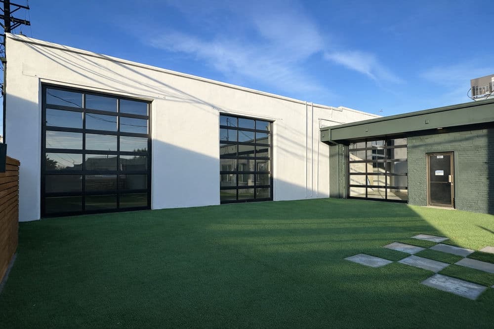 Modern building exterior with large windows, green yard, and clear blue sky.